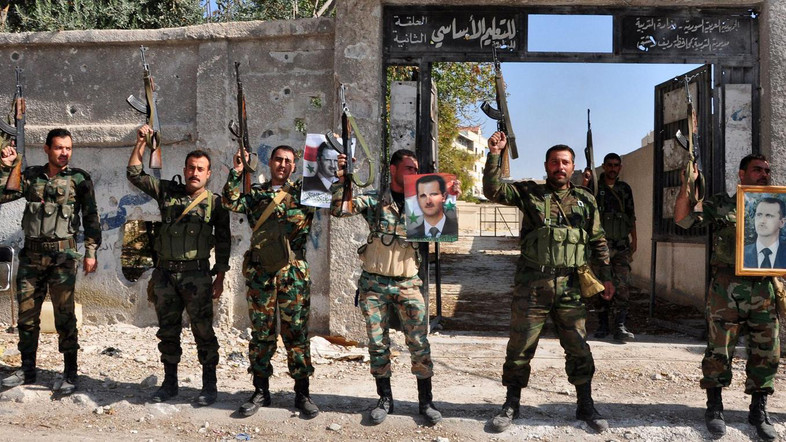 A handout picture released by the official Syrian Arab News Agency (SANA) on November 15, 2013 shows soldiers loyal to the regime posing with their weapons during the visit of an official in Sbeineh, south of the capital Damascus. Troops loyal to the regime backed by Lebanese Shiite Hezbollah fighters and other pro-regime militiamen retook Sbeineh, a major rebel enclave south of Damascus, the Syrian Observatory for Human Rights and state television said on November 8, 2013. On posters is Syria's President Bashar al-Assad.    AFP PHOTO SANA    === RESTRICTED TO EDITORIAL USE - MANDATORY CREDIT "AFP PHOTO/HO/SANA" - NO MARKETING NO ADVERTISING CAMPAIGNS - DISTRIBUTED AS A SERVICE TO CLIENTS ===
