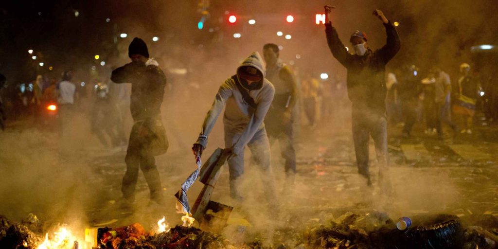 Demonstrators block a street with a burning barricade in the Altamira neighborhood of Caracas, Venezuela, Wednesday, Feb. 19, 2014. Venezuelan security forces backed by water tanks and tear gas dispersed groups of anti-government demonstrators who tried to block Caracas' main highway Wednesday evening. (AP Photo/Rodrigo Abd)