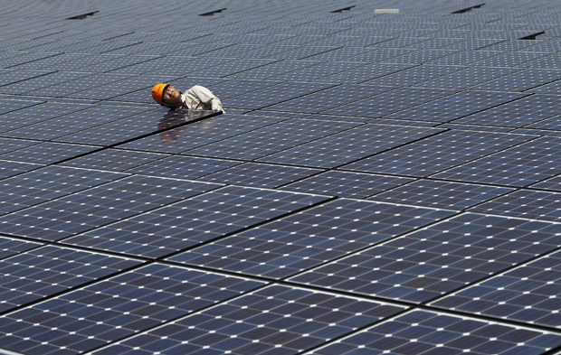 A worker checks solar panels at a solar power field in Kawasaki, near Tokyo in this July 6, 2011 file photo. Japan's subsidies for renewable power suppliers have sparked more than $2 billion of investment since they were launched two months ago, as companies and homeowners try to profit from an anti-nuclear energy policy after 2011's Fukushima crisis. Picture taken July 6, 2011. To match story JAPAN-ENERGY/RENEWABLES    REUTERS/Toru Hanai/Files (JAPAN - Tags: POLITICS BUSINESS ENERGY ENVIRONMENT)